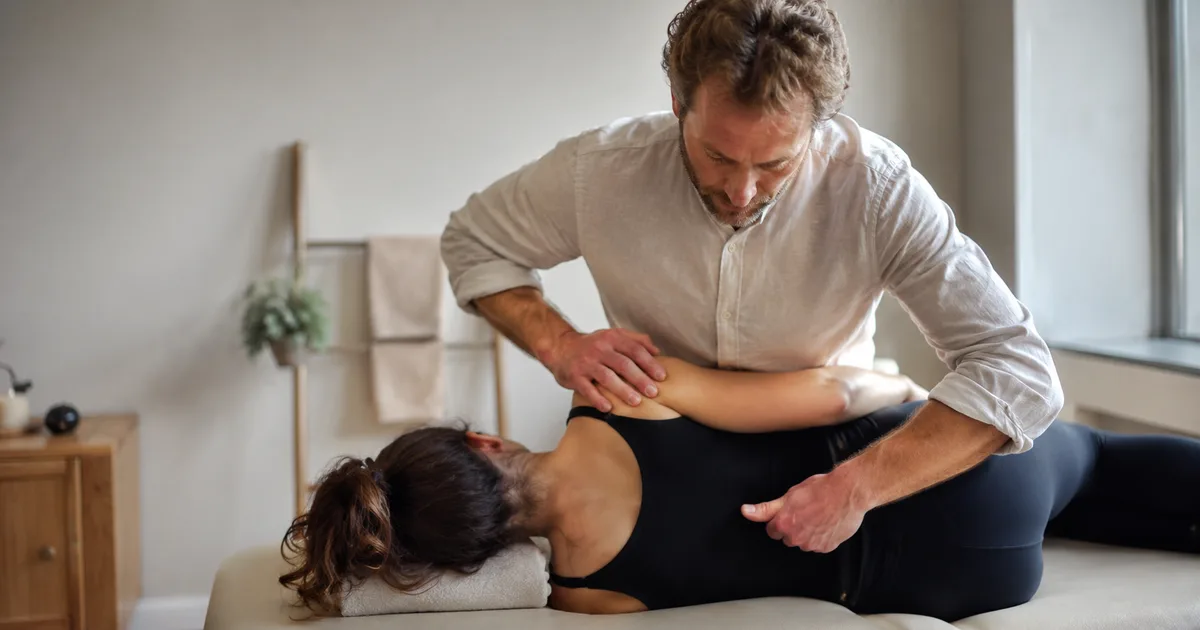 Ostéopathe en séance dans un cabinet lumineux, en consultation avec un patient adulte