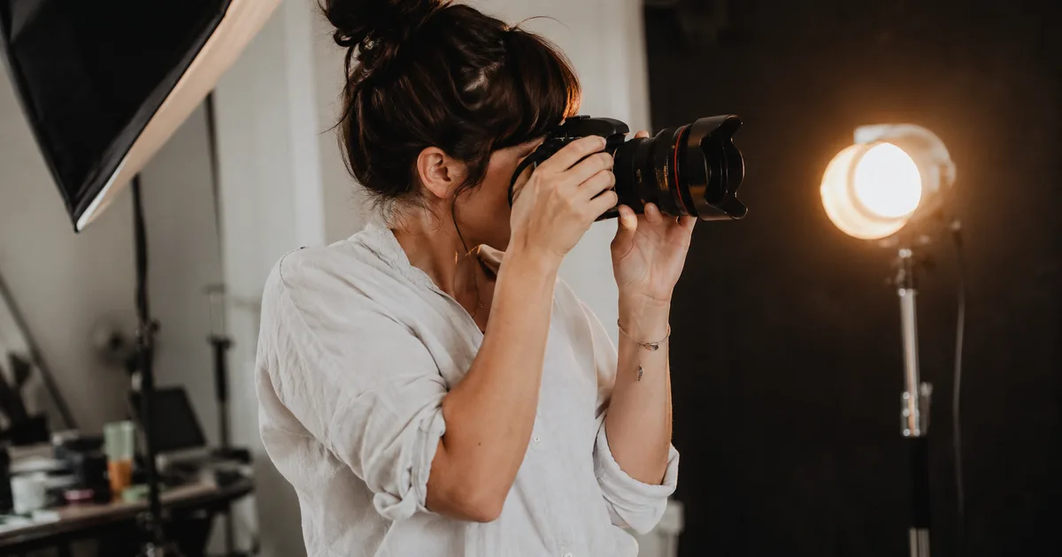 Page tarifs d'un site de photographe affichée sur un ordinateur portable, à côté d'un appareil photo et de tirages posés sur un bureau